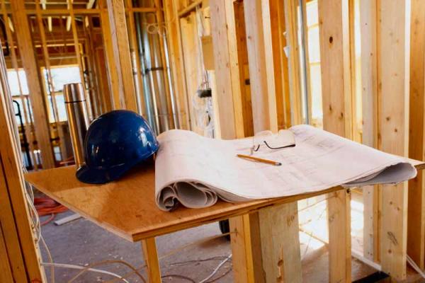 Construction hat and architectures plan inside house under construction